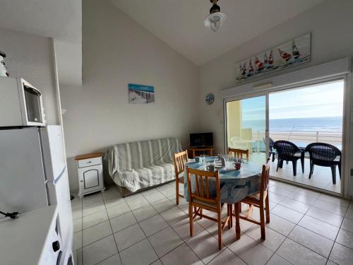 Il dispose d'une cuisine et d'un salon avec une table et un réfrigérateur. dans l'établissement Appartement T2 + Mezzanine avec 2 Salles d'Eau et Parking Privé, Bord de Mer - St-Hilaire-de-Riez - FR-1-323-336, à Saint-Hilaire-de-Riez