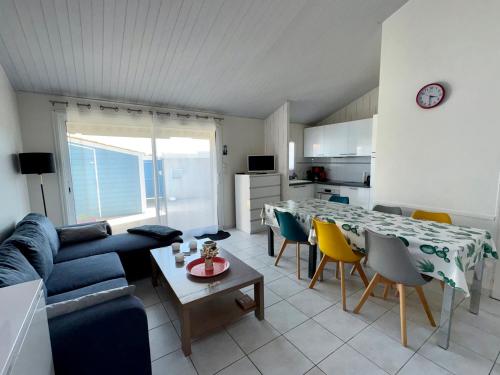 un salon avec un canapé, une table et des chaises dans l'établissement Maison pour 8 à 200m de la plage avec Wi-Fi gratuit - Saint Hilaire de Riez - FR-1-323-407, à Saint-Hilaire-de-Riez