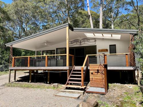 a house with a porch and a staircase in front of it at Alexander's Cottage, Pebbly Beach in East Lynne