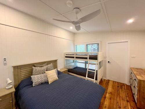 a bedroom with a bed with a ceiling fan at Alexander's Cottage, Pebbly Beach in East Lynne