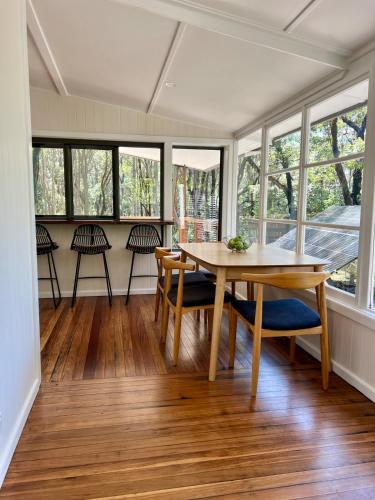 a dining room with a table and chairs and windows at Alexander's Cottage, Pebbly Beach in East Lynne