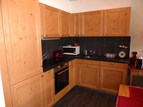 a kitchen with wooden cabinets and a microwave at Hotel Mont.Lac in Champex