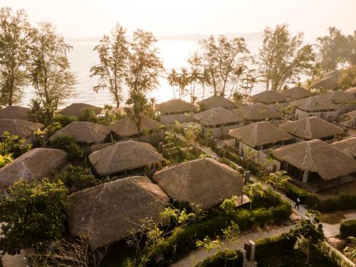a group of huts with straw roofs and the ocean at JATI Koh Russey in Sihanoukville
