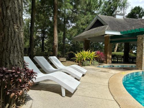 una fila de sillones blancos junto a una piscina en Alpine Crosswinds Standard 1BR Suite, en Tagaytay