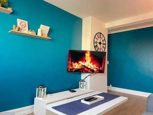a living room with a tv on a blue wall at appartement tout confort à 10min Paris la Défense in Bezons