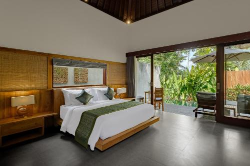 a bedroom with a large bed and a balcony at Elitya Ubud Villa in Ubud