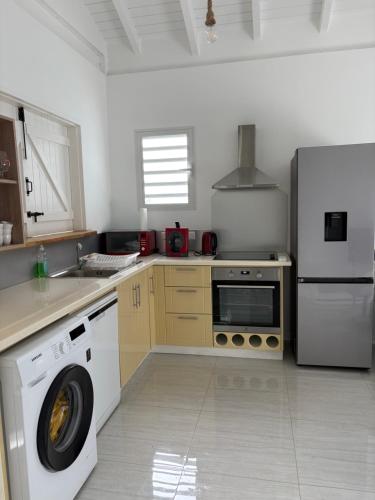 a kitchen with a washing machine and a refrigerator at Le Paradis de la Guadeloupe in Pointe-Noire
