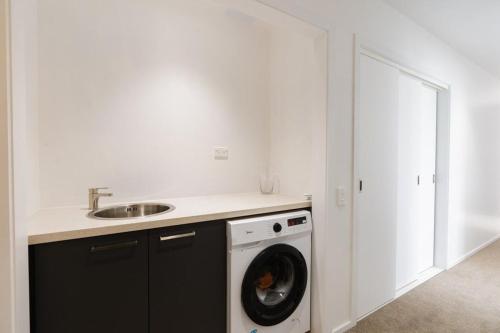 a kitchen with a washing machine and a sink at Private luxury townhouse close to central city in Dunedin