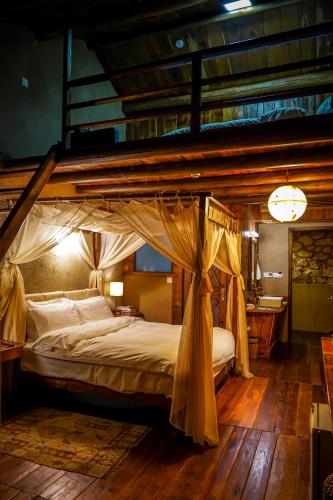 a canopy bed in a bedroom with a wooden floor at 温岭海山生活石屋民宿 in Shangma
