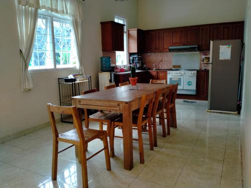 a kitchen with a wooden table with chairs and a refrigerator at Villa Tamu Ibu in Beran-kidul