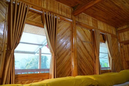 a bedroom with wooden walls and a large window at Homestaychivieng in Yên Minh