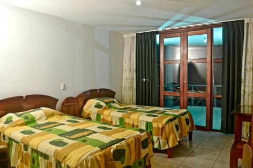 a hotel room with two beds and a window at Ecolodge El Palmero in Mazamari