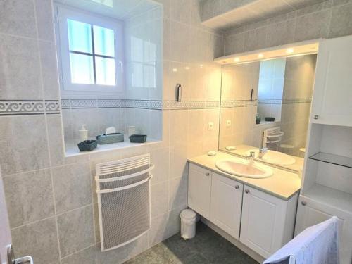 Un baño blanco con lavabo y espejo. en Gîte de charme avec cheminée en Dordogne - FR-1-616-466, en Tourtoirac