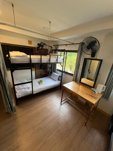 a room with bunk beds with a desk and a table at Lemonade Boutique Inn in Ko Lanta