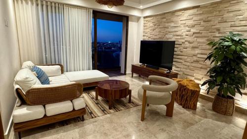 a living room with a television and a couch and a chair at Lujoso Penthouse con alberca vista increíble al Mar y Rio en el Estero in Boca del Río