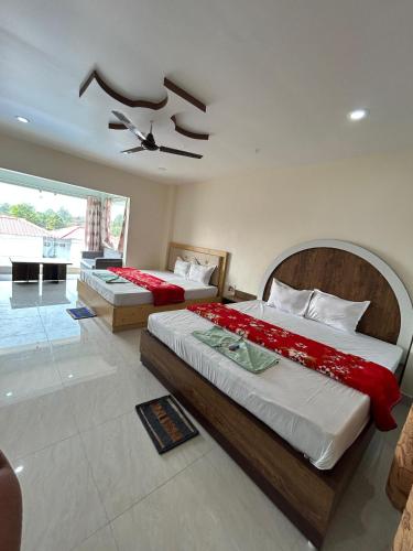 Un dormitorio con dos camas y un ventilador de techo. en Prantik Hotel And Resorts, en Tajpur
