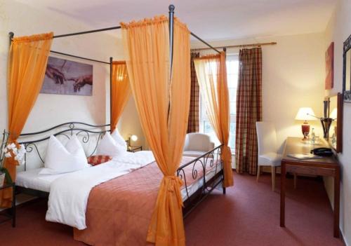 - une chambre avec un lit à baldaquin, un bureau et une chaise dans l'établissement Hotel Villa Magnolia, à Rödermark