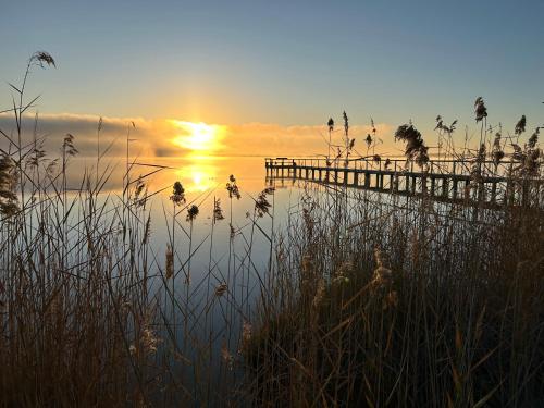 a sunset over a body of water with a pier at The Jetty House - Lake Bonney Riverland in Barmera