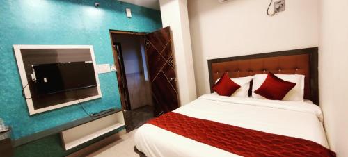 a bedroom with a bed and a flat screen tv at Aadya Inn New Luxury Hotel in Tirupati