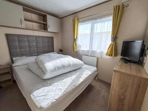 ハンスタントンにあるLovely Caravan With Decking At Manor Park In Hunstanton Ref 23091Tの大きなベッドとテレビのある寝室