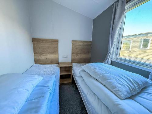 Dos camas en una habitación pequeña con ventana. en Lovely 8 Berth Caravan Ref 23028B, en Hunstanton