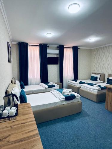 two beds in a room with blue carpet at Afsona Hotel in Bukhara