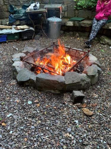 a fire pit with a person sitting next to it at The West Highland Way Campsite & Campervan Accommodation in Milngavie