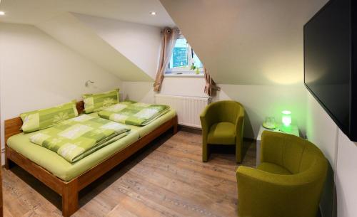 Göda的住宿－Pension Zum Hirsch，一间卧室配有一张床和两张绿色椅子