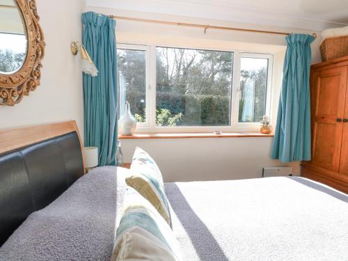 a bedroom with a bed with blue curtains and a window at The Lodge in Coltishall