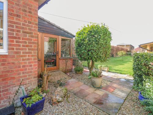 a garden with a brick house with a patio at The Lodge in Coltishall