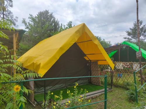 a yellow and black tent in a garden at Nisarg Camping Pods in Almora