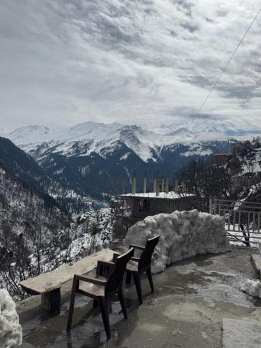 two benches sitting on top of a snow covered mountain at Cafekush tosh in Tosh