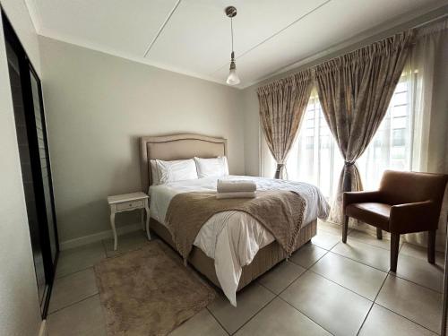 a bedroom with a bed and a chair and a window at The Blyde lagoon facing Pretoria in Pretoria