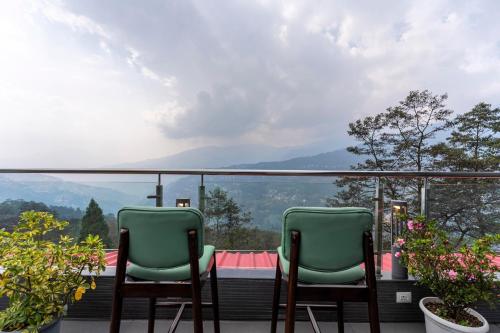 two green chairs sitting on a balcony with a view at Medalio Boutique Gangtok with Mountain View in Gangtok