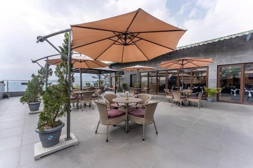 an outdoor patio with tables and chairs and umbrellas at Medalio Boutique Gangtok with Mountain View in Gangtok