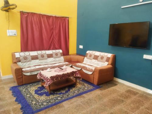 a living room with two couches and a flat screen tv at Private Villa With Swimming Pool at White Town in Puducherry