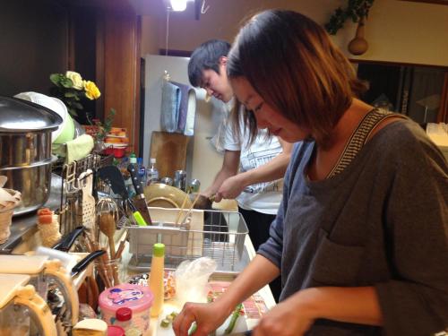 twee mensen die in een keuken eten klaarmaken bij Guest House Warabi in Mino