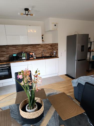 - une cuisine et un salon avec une table et un vase fleuri dans l'établissement Chez Sibylle Chevreuse Saclay, à Saint-Rémy-lès-Chevreuse
