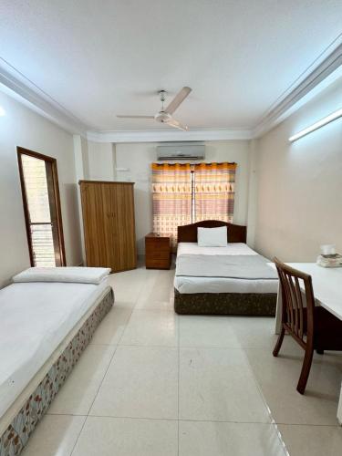 a bedroom with two beds and a table and chairs at Maya Eco Guest House in Dhaka