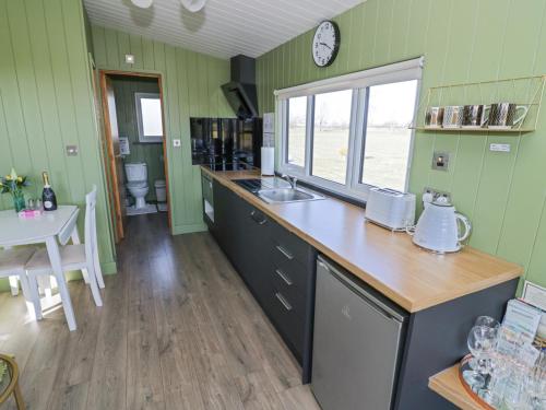 a kitchen with green walls and a counter and a table at Cotswold View 1 in Evesham