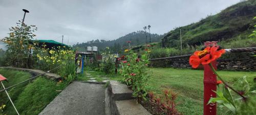 a garden with flowers and a fence with a pathway at Nisarg Camping Pods in Almora