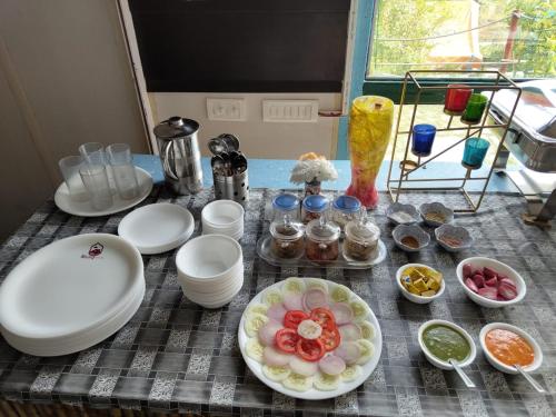 a table with plates and bowls of food on it at Nisarg Camping Pods in Almora