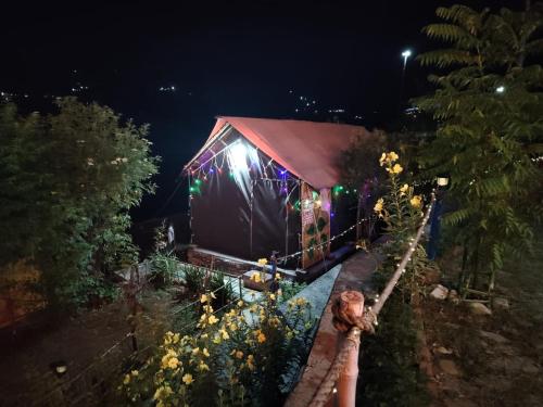 a lit up house with flowers in front of it at Nisarg Camping Pods in Almora