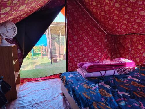 a bedroom with a tent with a bed and a window at Nisarg Camping Pods in Almora
