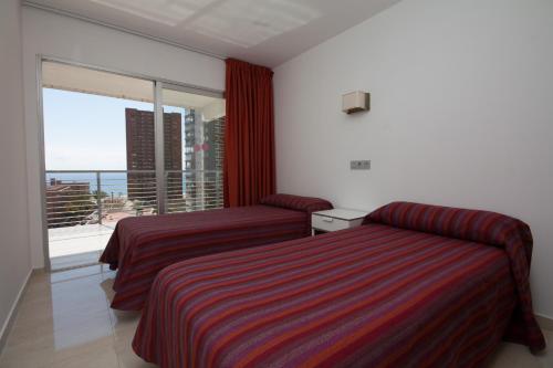 ベニドルムにあるApartamentos Nizaのベッド2台と大きな窓が備わるホテルルームです。