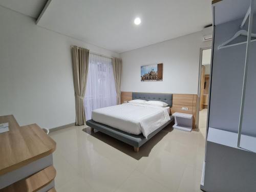 a white bedroom with a bed and a window at Roemah Audy in Yogyakarta