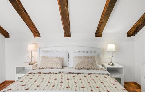 a white bedroom with a white bed with two lamps at Lovely Home In Krkovic in Prović