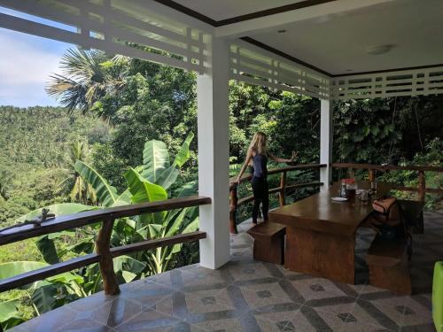a woman standing on the porch of a house at Puerto Galera Hilltop Guesthouse -Tropical Retreat in Puerto Galera