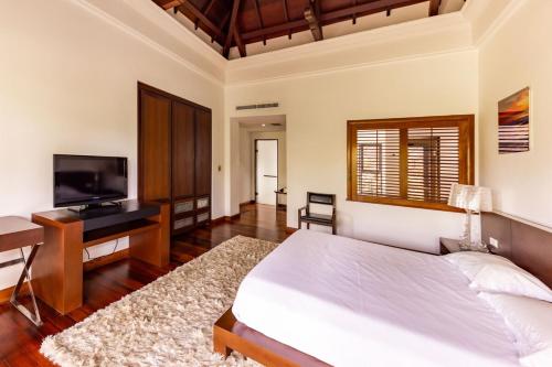 a bedroom with a bed and a desk and a television at Villa Serenity Cove by IHR in Bel Ombre