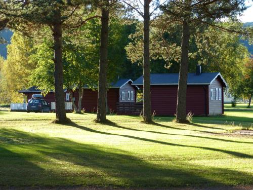 a red house with a group of trees in the grass at Björkebo Camping in Stöllet